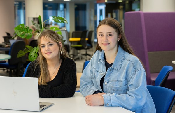 two student sitting in the library smiling