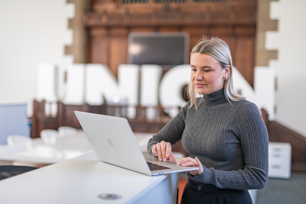 An image of our postgraduate alumni, Jordan, looking at her laptop for the find your course and entry requirements guide link. 