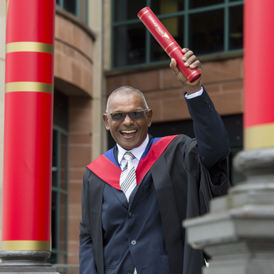 70 year old Ramgopaul who completed his Masters degree in Trindad via online learning after graduation, outside Usher hall. 