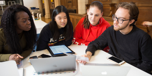 4 students sitting at a desk, working together on a project