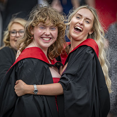 Two graduating students hugging.