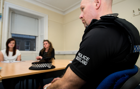 Police Scotland student placements at Torphicen Street Station sitting at a table talking to an officer