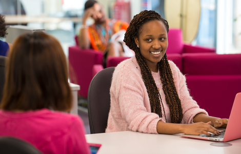 Photo of student smiling while using laptop
