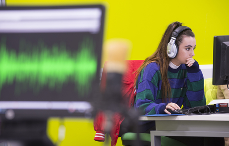 Student with headphones at computer working on an audio project