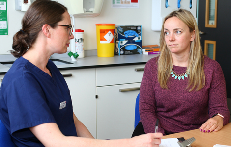 Female patient and nurse talking whilst sitting at a table in a consulting room