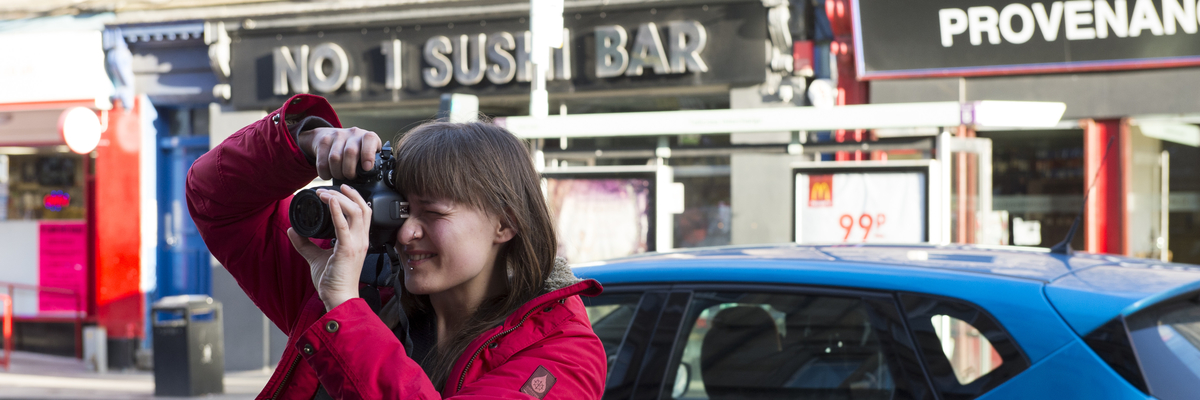 Girl holding up a camera to her eye for a photograph in Edinburgh