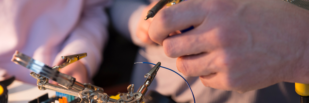 Close up of students hands building micro controllers