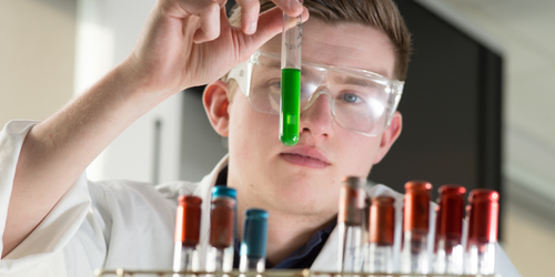 Student holding up a glass tube to the camera working in the microbiology lab