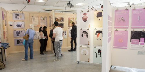 People walking around the room looking at the Degree show displays