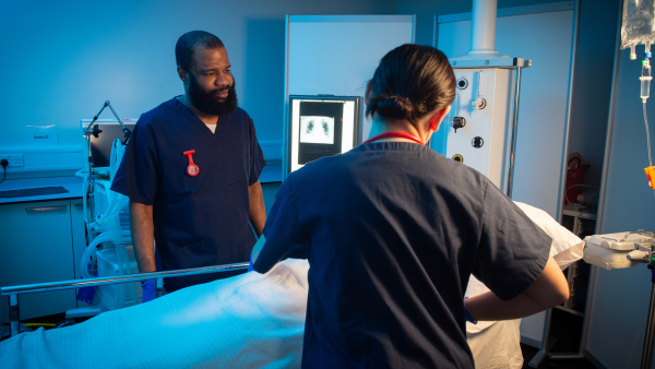 Two healthcare students prepare a patient bed in a clinical training environment