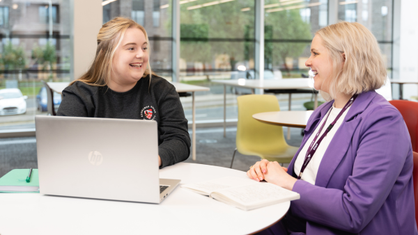Two people sitting a table smiling 