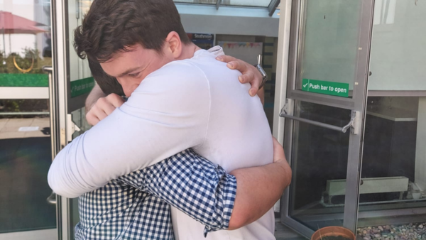 Two alumni hugging at event