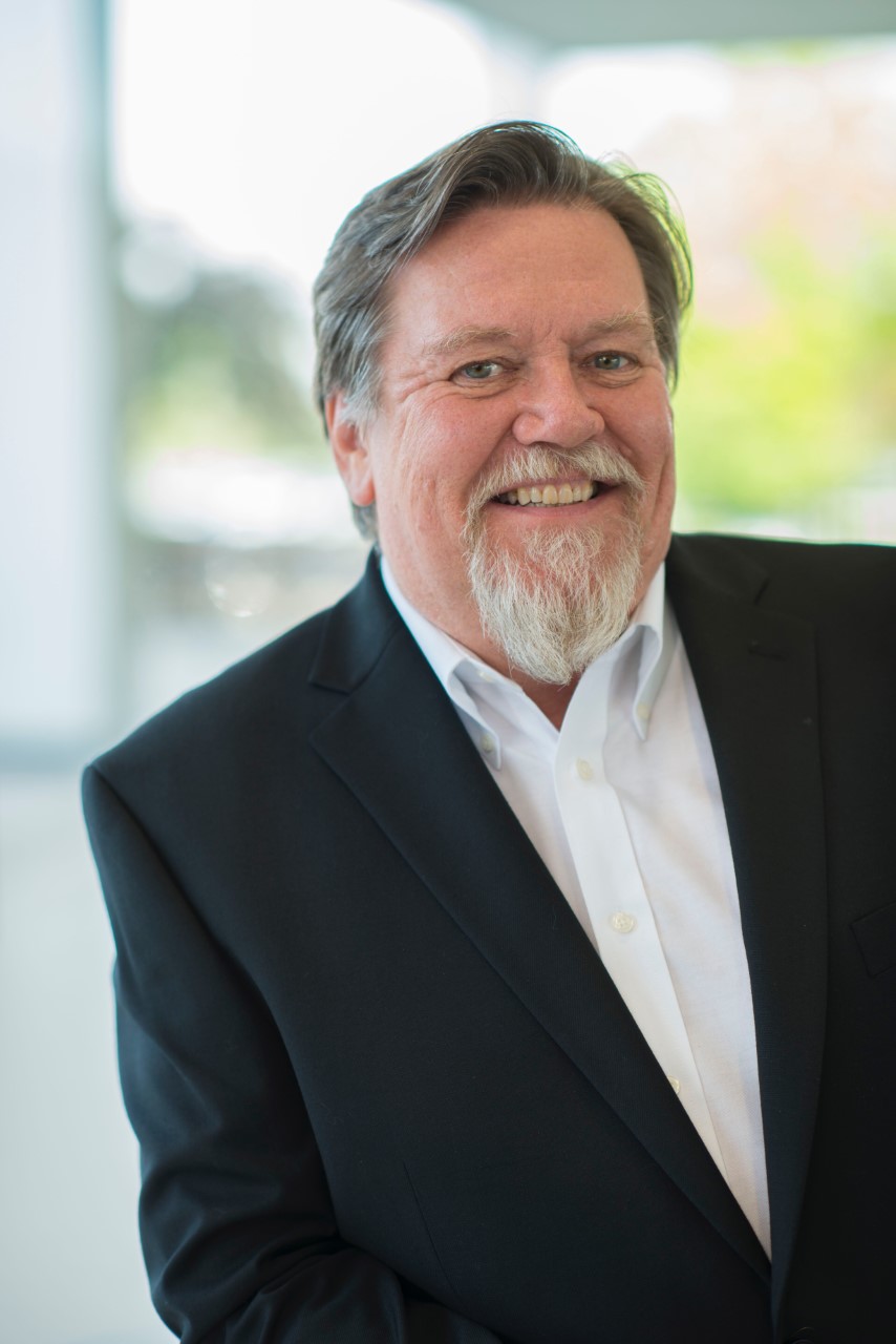 Moray Callum, wearing a dark-coloured suit and white shirt, smiling at the camera 