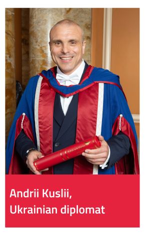 Honorary Graduate Andrii Kuslii wearing gown and holding scroll