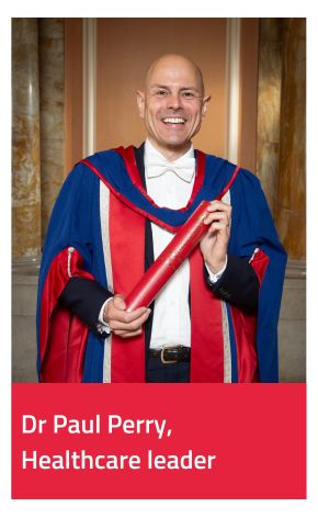 Honorary Graduate Paul Perry wearing gown and holding scroll 
