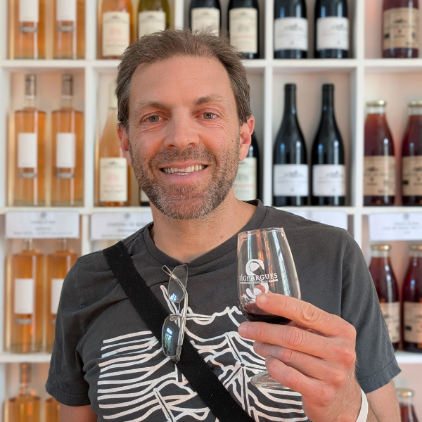 Alumnus Gregory Kinsman-Chauvet smiling and holding a glass of wine in Vivan Coop