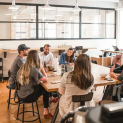 Group of people seated around a table in a modern office meeting room, collaborating during a discussion.