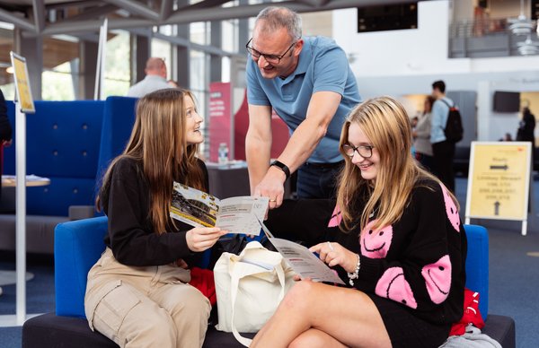 Students sat inside Craiglockhart campus, looking through leaflets with family at open day. 