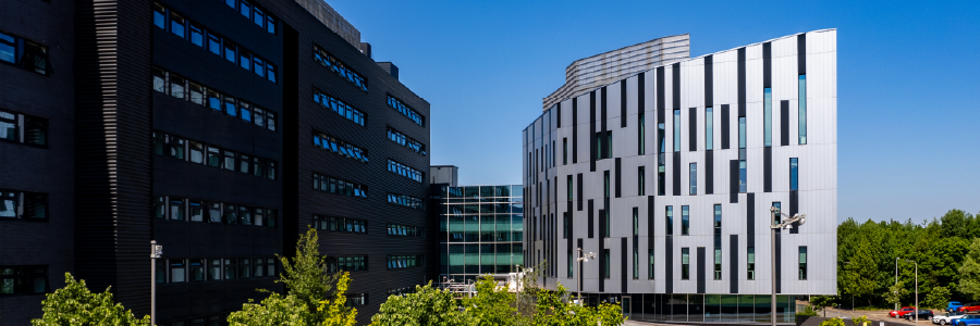 Modern university campus buildings under a clear blue sky