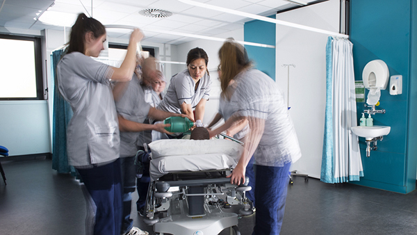 Five student nurses move so quickly they are blurred as they resuscitate a model patient in the simulation and skills centre. 