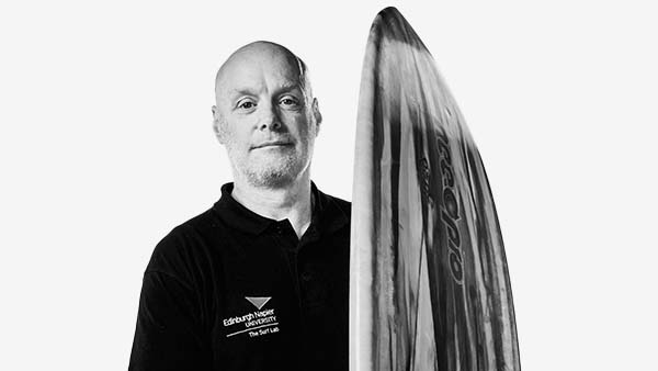 Brendon, co-founder of The Surf Lab, stands confidently with his surfboard