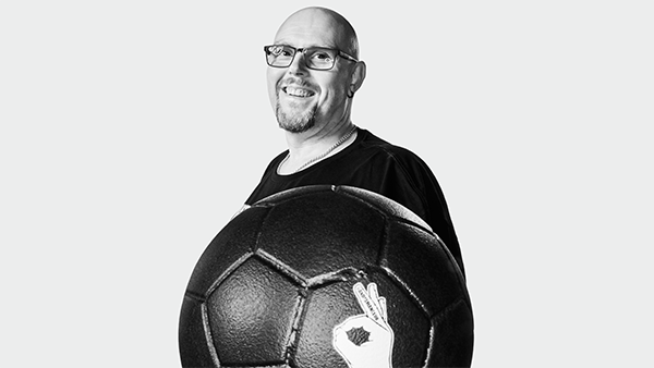 Ian Hounsome smiling and holding ANDYSMANCLUB football.