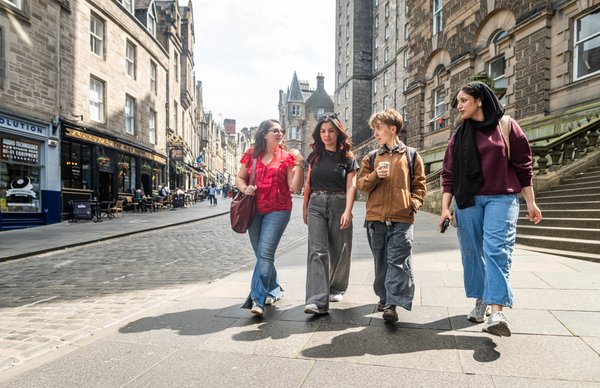 A photo of a group of Edinburgh Napier students sight-seeing in the city centre on a sunny day, strolling around Edinburgh's vibrant and famous old town streets.