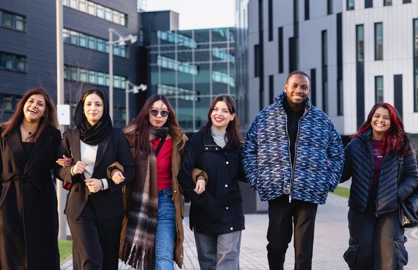 A photo featuring a group of students walking and talking as they stroll around Sighthill campus on a sunny autumn day. 