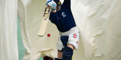 Person playing cricket hitting the ball with a bat. 
